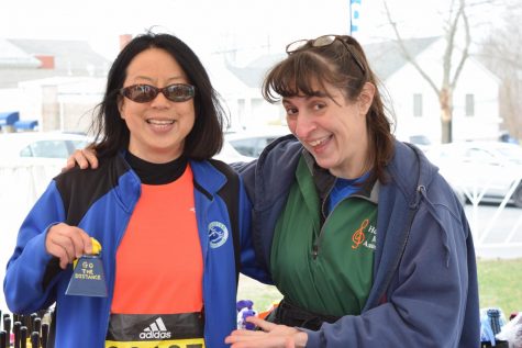Photo: Denise Antaki (left) visiting Kathy Curry's (right) booth at Hopkinton Common where she is selling bells to cheer the runners on.