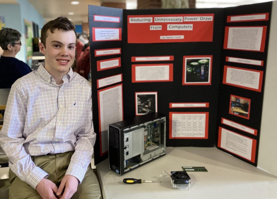 Nate Foster sitting beside his project board alongside some computer parts. Foster’s interest in computers and engineering led him to choose his Science Fair project. Foster’s project asks the question ‘How much power do computers really consume, and what should we do about it?’.