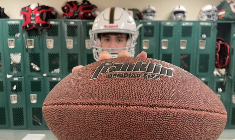 Braden Hicks, captain of the boys Varsity football team, holds out a football used during the team’s practices while gearing up in the boys lockeroom. Hicks has been present during all his offseason workouts along with his teammates to improve their skills with one goal in mind: “Win the TVL,” Hicks said.
