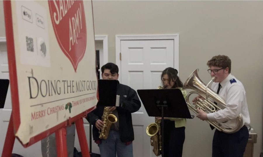 Members of the jazz ensemble play holiday carols next to a Salvation Army kettle.