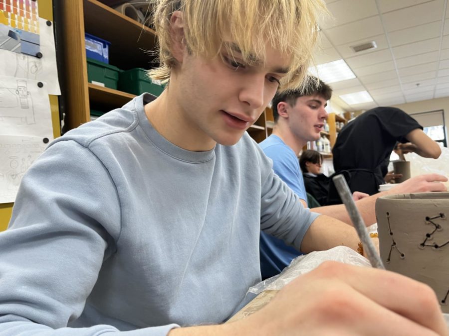 Max Nye works on a piece in ceramics class while discussing his future college life.