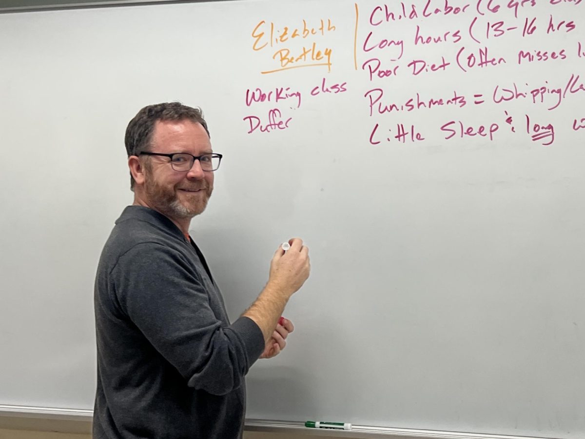 Mr. Wilander writes on the whiteboard during world history.