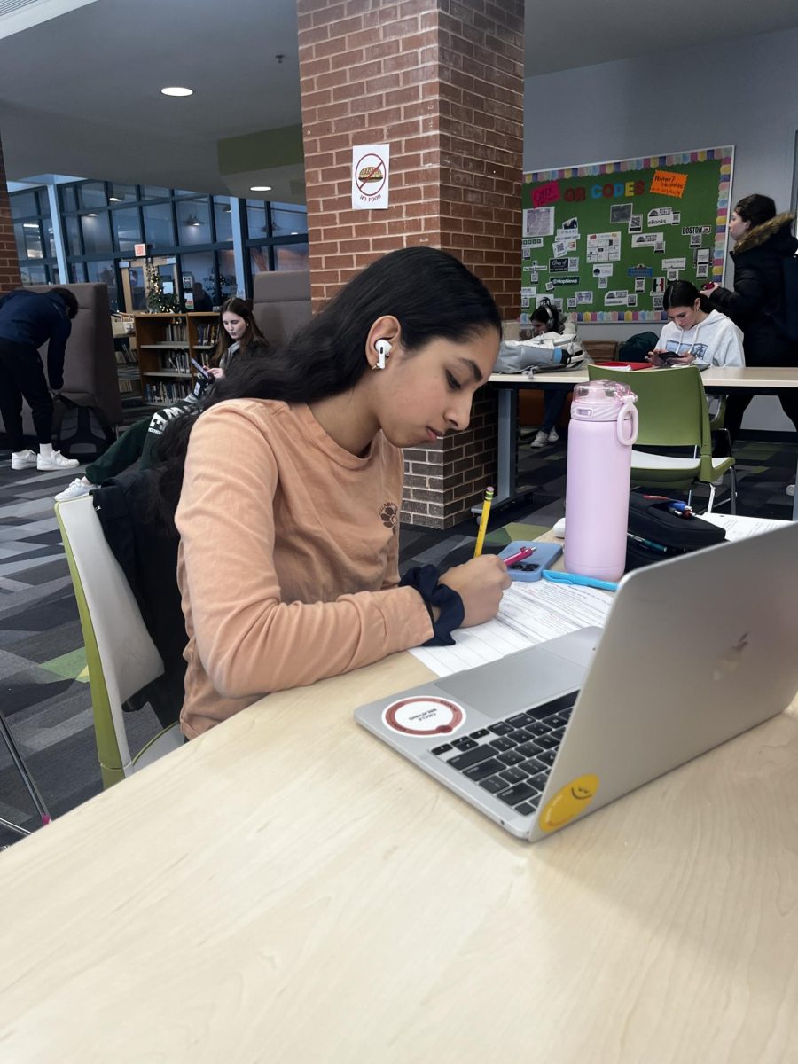 A student listening to music while doing work in the library.