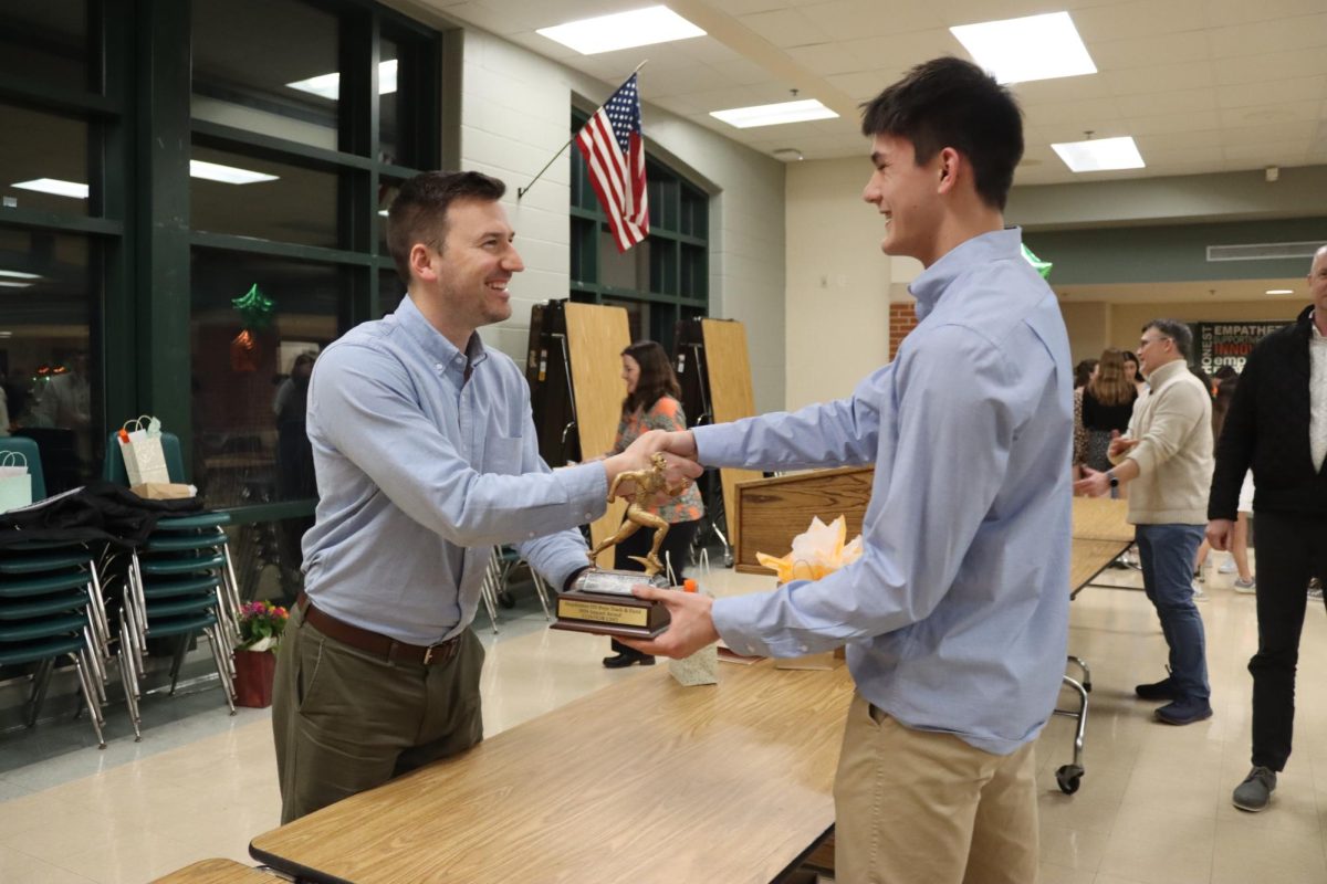 Cho accepts the Impact Award from jumps coach Brian Prescott at the Indoor Track banquet.