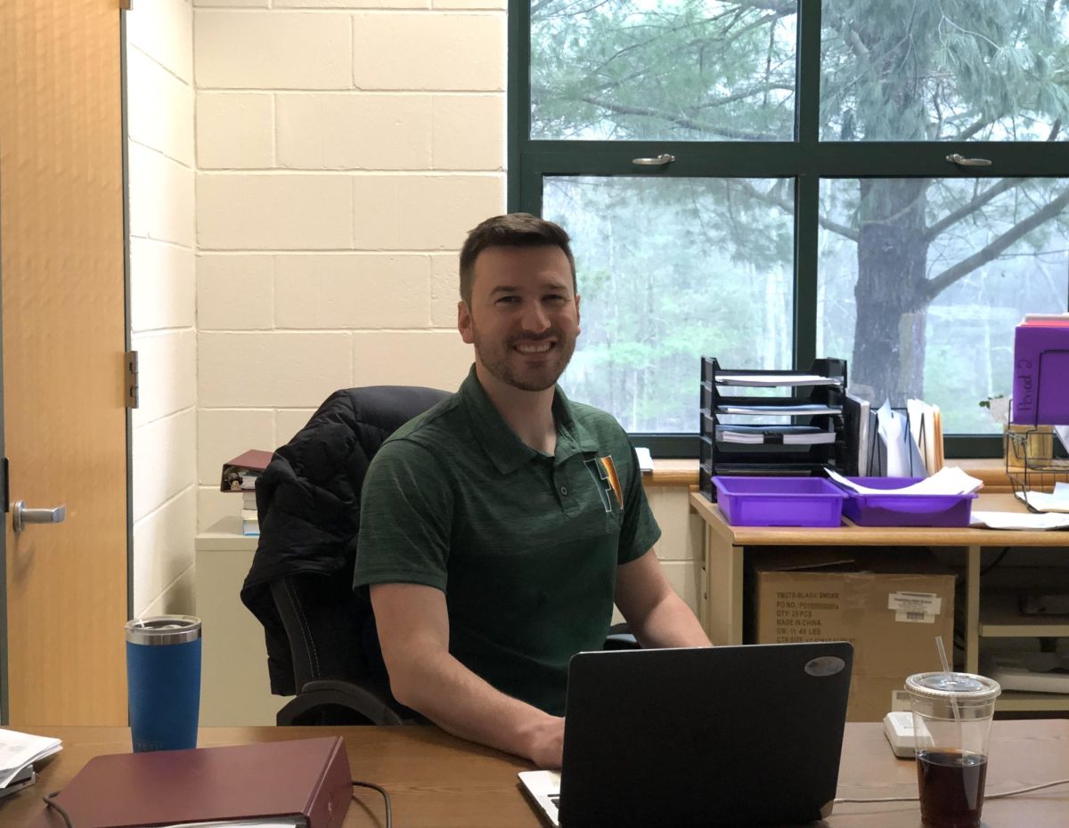 Caught In Action — Mr. Prescott is sitting at his desk as he watches over his flex block group. When coming in to interview him, he was in a lighthearted debate with two other students about a math equation. “And the world is big and bright, so I might not go and look at it, but I happen to stay here.” 