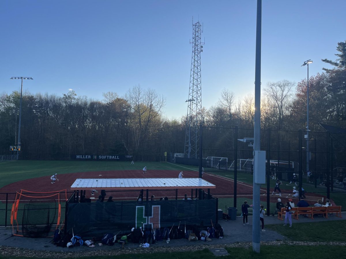 The Hopkinton Hiller dugout in their most recent game, girls in the outfield waiting for the pitch.
